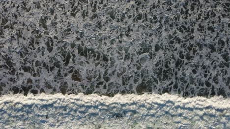 A-top-down-shot-of-waves-moving-across-the-screen,-with-beautiful-patterns-in-the-swell-of-the-wave