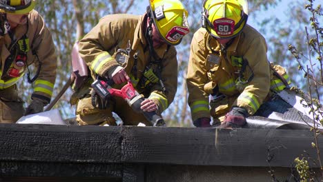 Close-up-of-Firefighters-cutting-a-roof,-to-get-inside-a-burnt-building-in-Los-Angeles,-USA