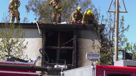 Firemen-drilling-through-the-roof-of-a-burnt-building,-in-Los-Angeles,-USA
