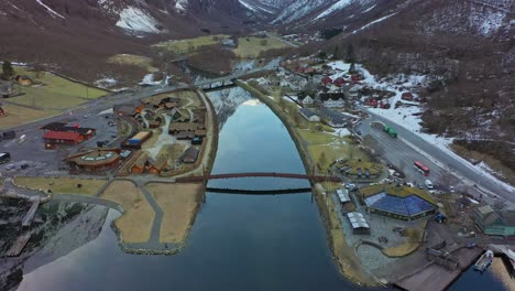Gudvangen-village---Upward-moving-aerial-with-tilt-down---Beautiful-town-overview-with-river-in-center-of-frame-and-reflections-in-sea-surface