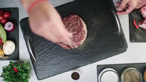 Close-up-of-shot-of-a-Chef-Seasoning-A-Beef-Steak-with-salt-and-pepper-on-a-cutting-board