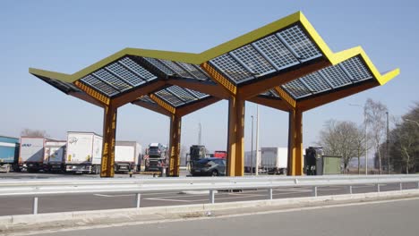 Amplio-ángulo-De-Estación-Eléctrica-Con-Panel-Solar-Junto-A-La-Autopista-Con-Coche-Cargando-La-Batería---Lovaina,-Bélgica