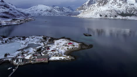 Aerial-flyover-Sildpollnes-Church-with-scenery-winter-landscape-in-background,-snow-covered-mountains,-Lofoten-Norway