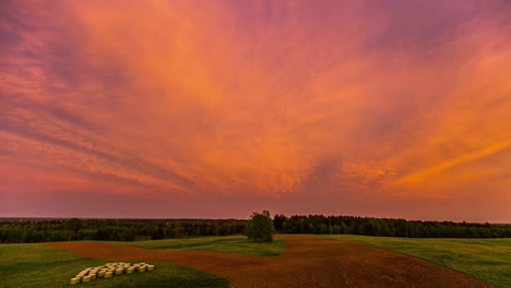 Cirrostratus-Clouds-flying-over-yellow-and-red-colored-sky-during-golden-hour-in-countryside---Time-lapse-footage