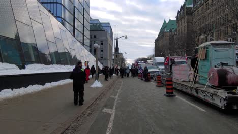 Freedom-Convoy-protest-in-Ottawa-downtown-with-many-people-and-truck-block-road,-motion-view