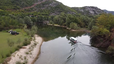 Tuoboat-Turístico-Navega-Sobre-El-Río-Crnojevica-Hasta-El-Lago-Skadar,-Montenegro---Dolly-Aéreo