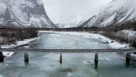 Icy-river-with-small-bridge-near-Åndalsnes,-western-Norway-in-the-winter