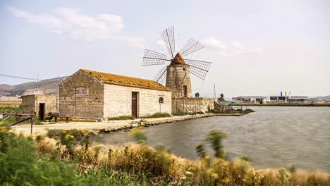 People-watching-old-building-with-windmill-at-Salt-Pans-Reserve-during-sunny-day-on-Sicily