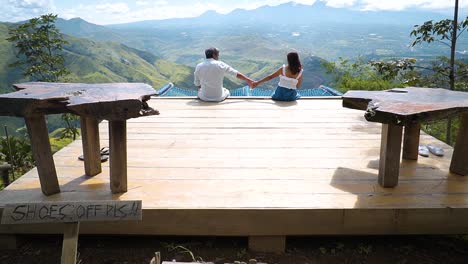 couple-dating-on-top-of-mountain,-holding-hands-enjoying-each-other's-company