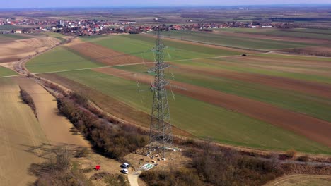 Aerial-View-Of-Electricity-Pylon-Overlooking-Field-In-Rural-Town
