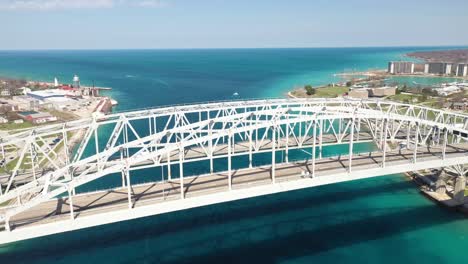 Blue-Water-Bridge-connecting-Port-Huron,-Michigan-USA-and-Sarnia,-Ontario-Canada-with-drone-moving-down
