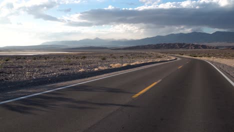 Carretera-Solitaria-Con-Giro-Cruzando-El-Valle-De-La-Muerte,-Desierto-De-Mojave,-California,-Tiro-Izquierdo-De-Dolly