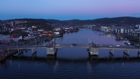 Porsgrunn-city-bridge---Late-evening-aerial-showing-traffic-passing-ove-channel-bridge-at-dawn---Calm-water-in-channel-below-and-clear-sky