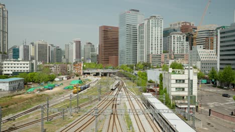 Railway-Train-Departing-from-Seoul-Station-Depot-with-High-rise-Buildings-in-Background,-South-Korea