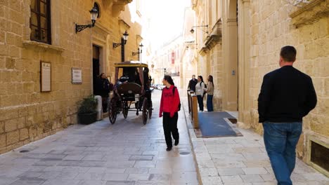 Tourists-walk-in-Mdina-streets-while-horse-carriage-passes-by