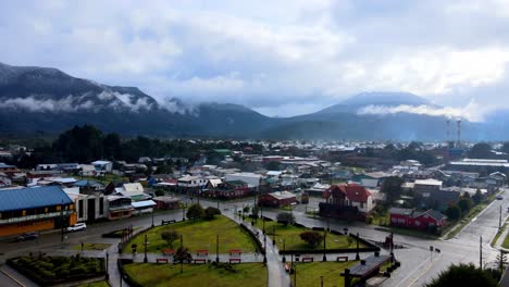 Aerial-view-dolly-in-from-the-main-square-of-Hornopiren,-Chile,-Hornopiren-volcano-in-the-background-covered-by-clouds