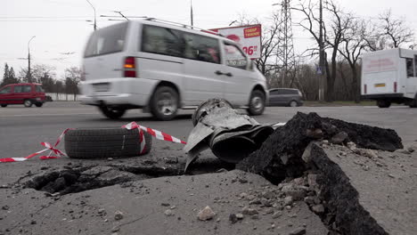 Vehicles-drive-past-a-missile-that-was-shot-down-and-the-wreckage-crashed-and-embedded-into-the-tarmac-of-a-road-during-the-Russian-invasion-of-Ukraine