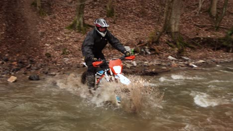 Elektro-Motocross-Bike-Trial,-Der-Durch-Schmutzigen-Fluss-Spritzt,-Wasser-Und-Schlamm-Spritzt,-Extremes-Spaßsport-Offroad-Motorradfahrer-Abenteuer-In-Zeitlupe-Im-Waldgelände