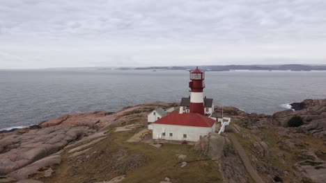 Beautiful-lighthouse-with-lighthousekeepers-cabin-at-Ryvingen-in-southern-Norway---Idyllic-location-in-Norway-southern-coast---Aerial-flying-towards-lighthouse-tower-and-passing-really-close