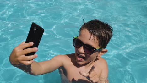 Kleiner-Junge-Vergnügt-Sich-Im-Schwimmbad,-Agiert-Vor-Der-Smartphone-Kamera,-Sommerkonzept