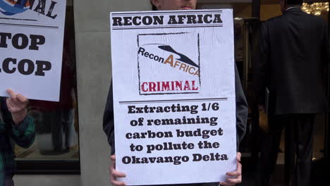 Ein-Klimaschutzdemonstrant-Hält-Während-Des-Afrika-Energiegipfels-Ein-Plakat-Vor-Dem-Mayfair-Hotel,-Auf-Dem-Er-Das-Energieunternehmen-Recon-Africa-Als-„kriminell“-Bezeichnet