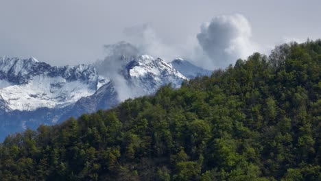 Malerischer-Grüner-Bergrücken,-Der-Wolken-Freigibt,-Die-Den-Spitzen-Alpengipfel-Umhüllen