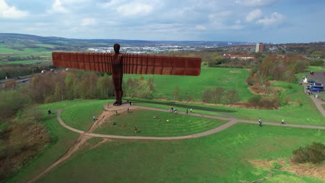 Tall-Copper-Structure-Of-The-Angel-Of-The-North-In-Gateshead,-Tyne-and-Wear,-England,-UK-With-Sight-Of-Extensive-Nature,-Buildings-And-Freeway-In-The-Background