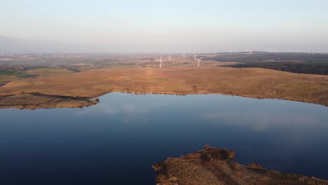 Aerial-approach-of-distant-wind-turbine-farm-in-rural-area-of-Scotland