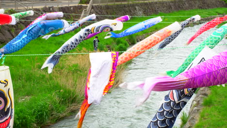 Matsumoto,-Nagano,-Ca.-2022-Mai:-Ein-Regnerischer-Frühlingstag-Mit-Vielen-Bunten-Karpfenschlangen,-Einem-Japanischen-Maibrauch,-Die-Angenehm-Im-Wind-Auf-Dem-Fluss-Schwimmen