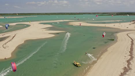 Zahlreiche-Kitesurfer-Spielen-In-Der-Türkisfarbenen,-Flachen-Brasilianischen-Bucht