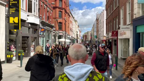 Slow-motion-walk-showing-crowd-of-pedestrian-in-city-center-of-Dublin-Downtown-during-sunny-day---Shopping-road-with-shops-and-pubs-in-summer