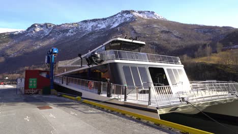 Walking-towards-unique-passenger-sightseeing-boat-Future-of-the-fjords-while-alongside-in-Flam-Norway---Blue-sky-and-mountain-background-with-electric-boat-in-front