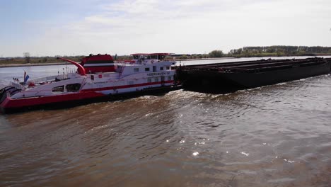 Aerial-Circle-Dolly-Around-Stern-Of-Veerhaven-Pushtow-Ship-Transporting-Empty-Barges-Along-Oude-Maas