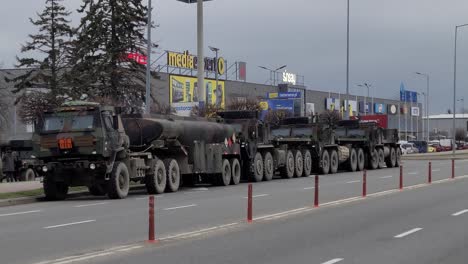 Military-trucks-in-a-city-street-next-to-a-commercial-district
