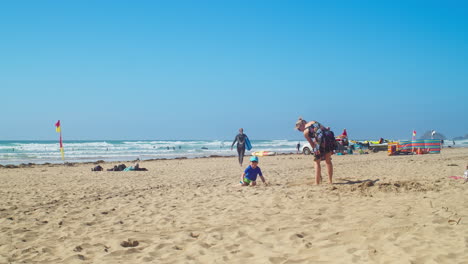 Mutter-Und-Kind-Spielen-Mit-Einer-Spielzeugschaufel-Im-Sand-Am-Strand-Von-Perranporth-In-Cornwall,-England