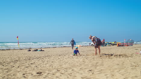 Madre-E-Hijo-Jugando-En-La-Arena-Con-Una-Pala-De-Juguete-En-La-Playa-De-Perranporth-En-Cornualles,-Inglaterra