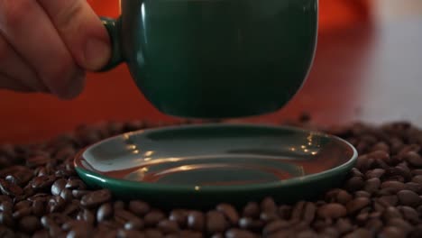 Footage-of-a-person-taking-a-cup-of-coffee-of-a-plate-and-placing-it-in-front-of-her-to-drink-it,-the-scenery-is-beautiful-decorated-with-coffee-beans-and-a-nice-green-cup