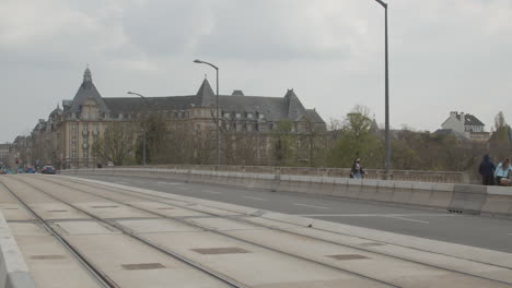 Woman-wearing-facemask-walking-over-Adolphe-Bridge-with-old-town-of-Luxembourg-in-the-background
