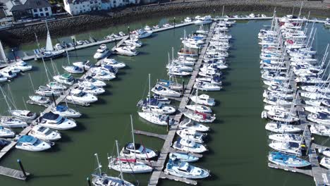 Flying-above-luxury-yachts-and-sailboats-reflections-on-sunny-Conwy-marina-birdseye-aerial-view-rise-right