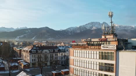 Tygodnik-Podhalanski-Building-In-Cityscape-With-Snowcapped-Mountains-In-Background-At-Zakopane,-Poland