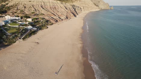 One-person-alone-walking-on-the-sand-beach,-Praia-da-Luz,-Algarve