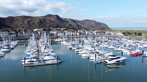 Luxury-yachts-and-sailboats-mooring-in-Conwy-Wales-colourful-sunny-mountain-marina-Aerial-low-left-dolly-view