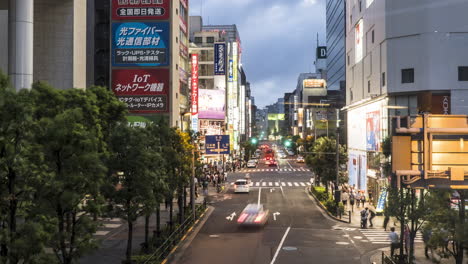 Buildings-At-Akihabara-Street-With-Bustling-Traffic-And-People-Walking-At-Night-In-Taito-City,-Tokyo,-Japan