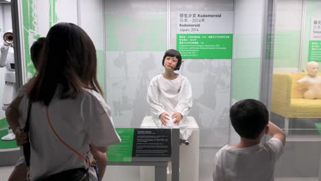 Besucher-Gestikulieren-Während-Der-„Roboter“-Ausstellung-Im-Hong-Kong-Science-Museum-In-Hongkong-Auf-Den-Japanischen-„Kodomoroid“-Roboter