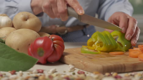 Woman-cutting-pepper-vegetable-in-home-kitchen