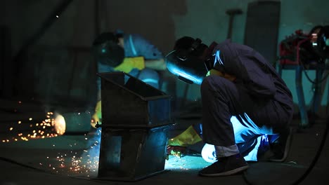 Male-worker-grinding-butt-weld-pipe-in-metalwork-workshop