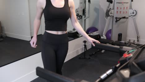 Sporty-girl-stepping-on-to-Bowflex-treadmill-in-empty-gym,-slow-motion-closeup