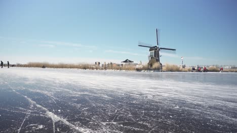 Eislaufen-Auf-Gefrorenen-Holländischen-Kanälen-In-Der-Nähe-Traditioneller-Windmühlen,-Winterlandschaft