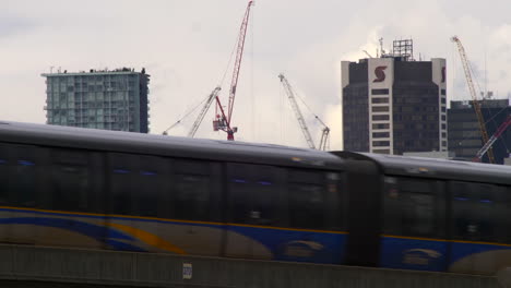 Edificios-En-Construcción-En-El-Distrito-Central-De-Negocios,-El-Centro-De-Vancouver,-Columbia-Británica-Con-El-Tren-A-Toda-Velocidad-En-La-Vía-En-Primer-Plano