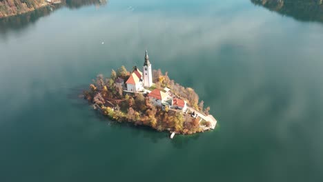 Aerial-view-of-Lake-Bled-Island-during-the-autumn-season-as-the-drone-comes-down-to-show-more-of-Bled-in-the-background